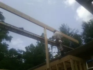Carpenter setting a ridge beam over a new addition frame — Ice Dam Removal by Roofing Brothers in Spartanburg
