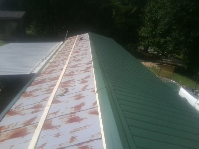 Old rusted panels beside newly installed green metal roofing — Wind Damage Roof Repair by Roofing Brothers in Spartanburg