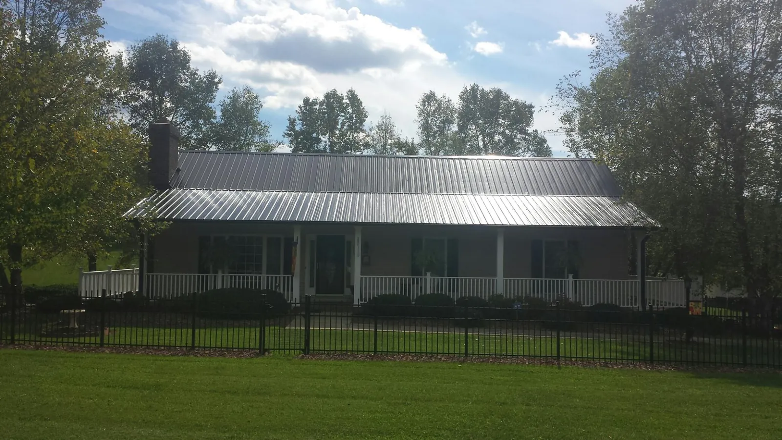 Gray metal roof on a brick ranch with a full width front porch — Gutter Guard Installation work by our crew in Spartanburg