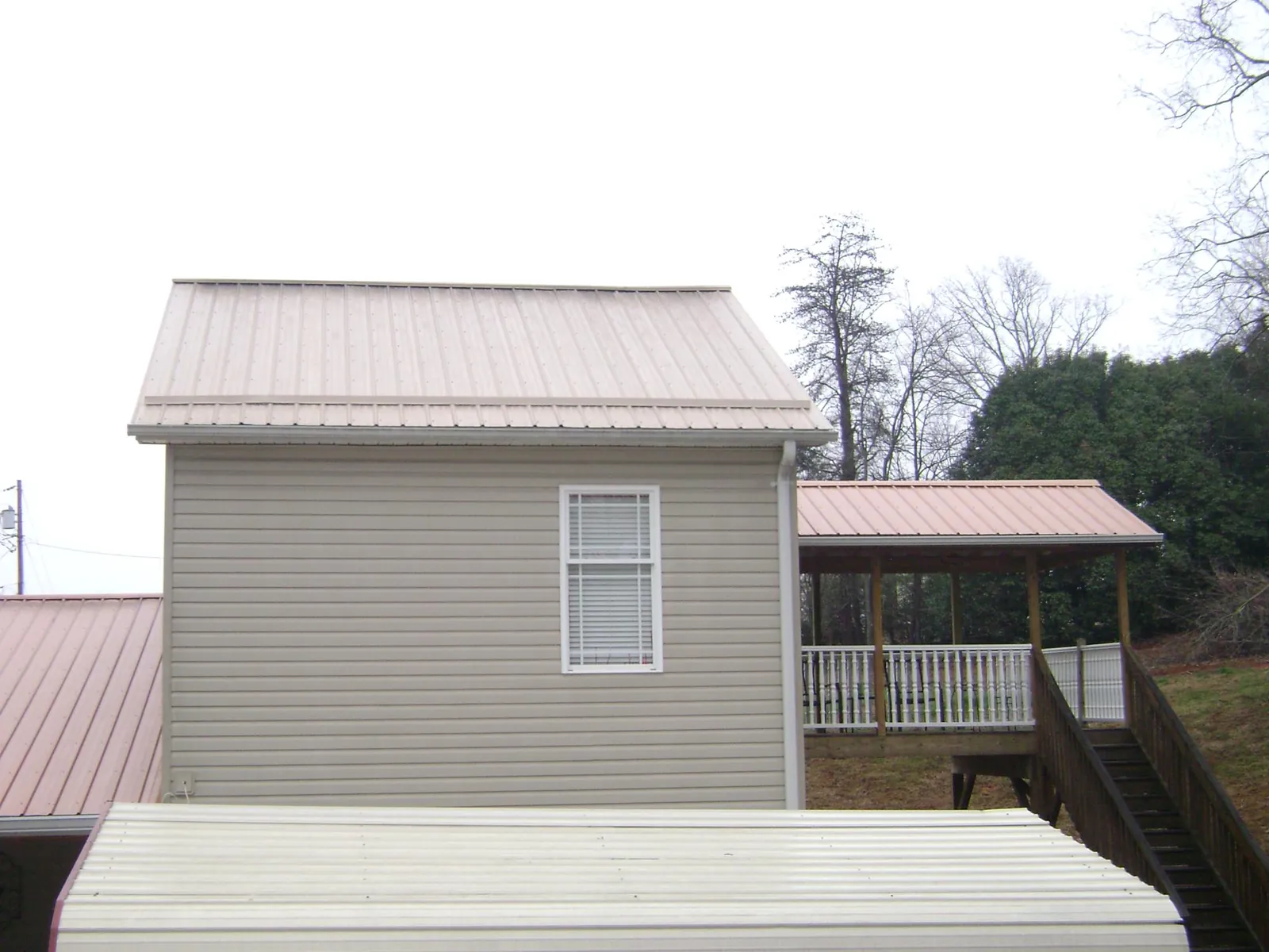 Tan metal roofs on a two story addition and attached porch, from a Roof Replacement job in Spartanburg