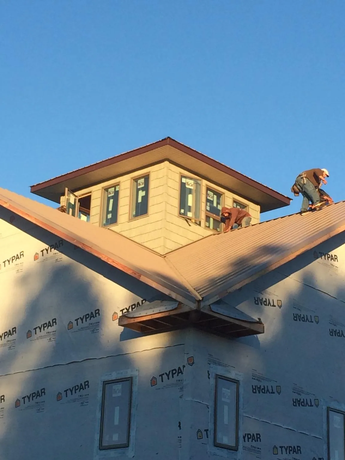Roofers working around a rooftop cupola on a new metal roof at sunset — Roof Waterproofing in Spartanburg by Roofing Brothers